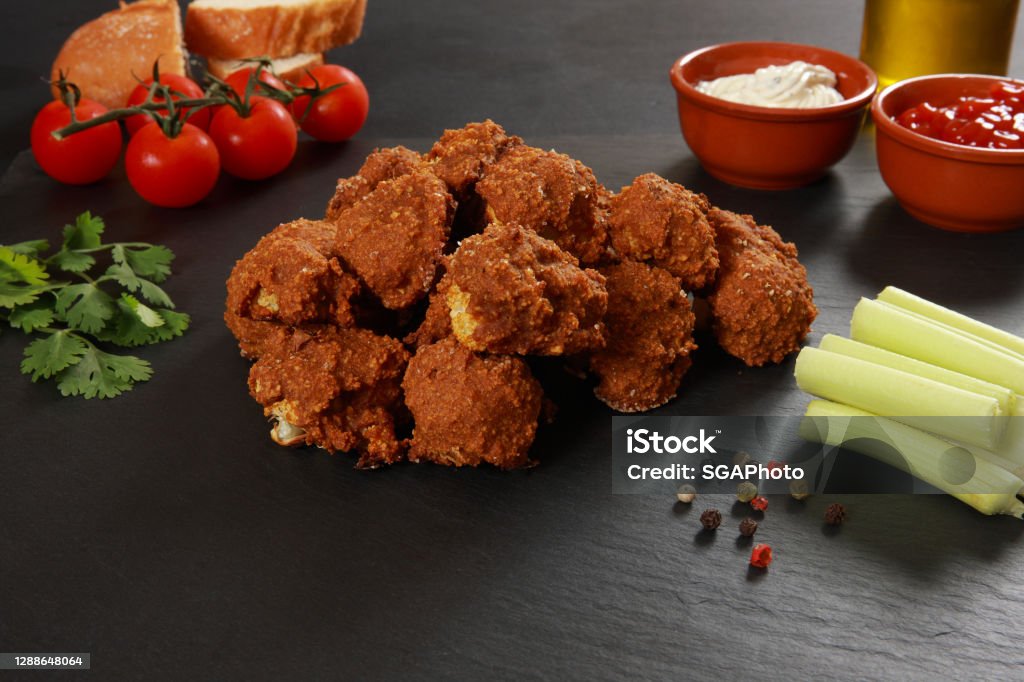 Freshly baked in breadcrumbs and much paprika powder Cauliflower Buffalo Wings on black background
