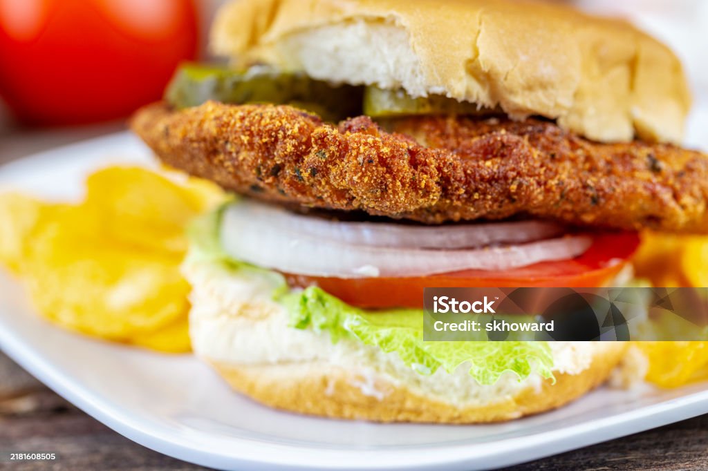 Breaded pork tenderloin sandwich with lettuce, tomato, onion, pickles and mayo.
