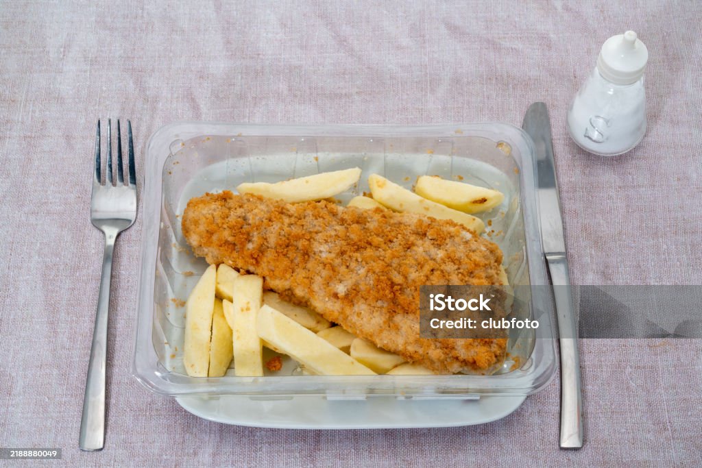 An uncooked TV ready meal of fish and chips on a plate